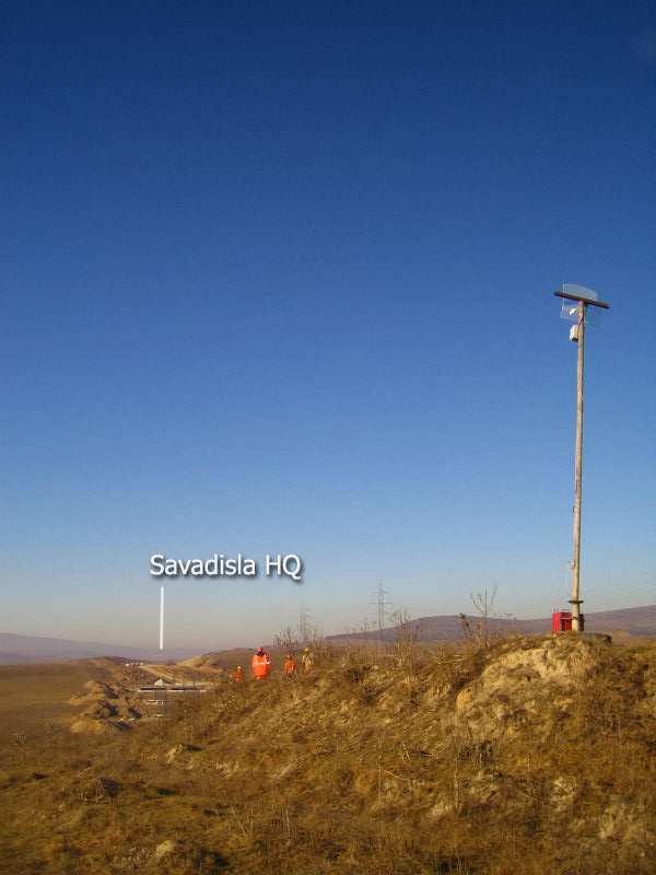 A wooden mast with an antenna on a rocky hilltop, with the Săvădisla HQ labelled in the valley below